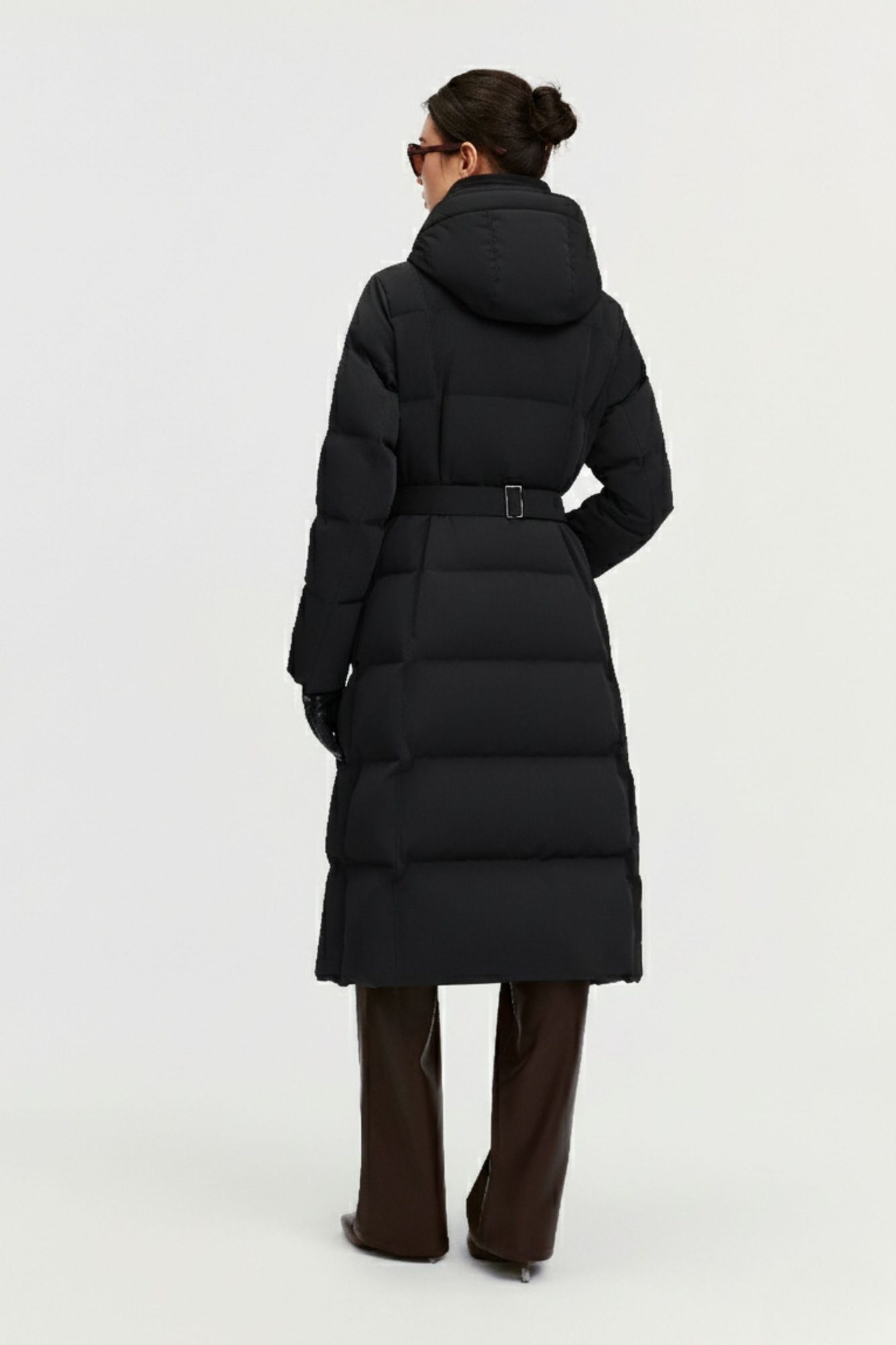 Back view of woman wearing black puffer coat with belt detail and hood